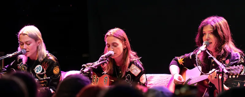 boygenius выступают на сцене 24 августа 2023 года, три участницы у микрофонов, концертное фото